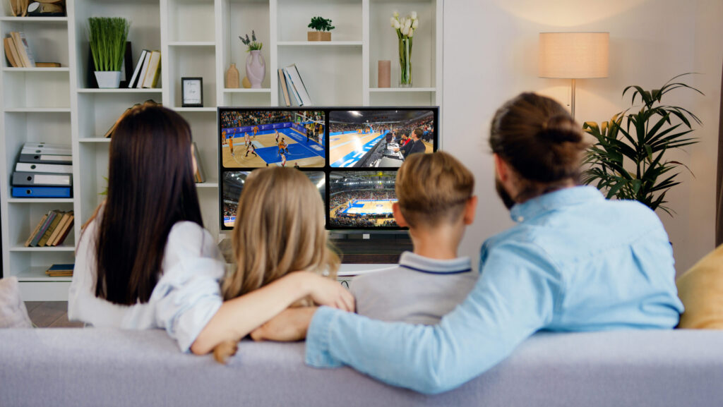 Family watching a multiview sports broadcast with four live basketball streams on TV